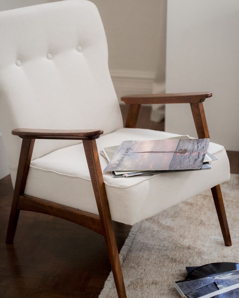 A mid-century lounge chair with cream bouclé upholstery and a solid teak frame