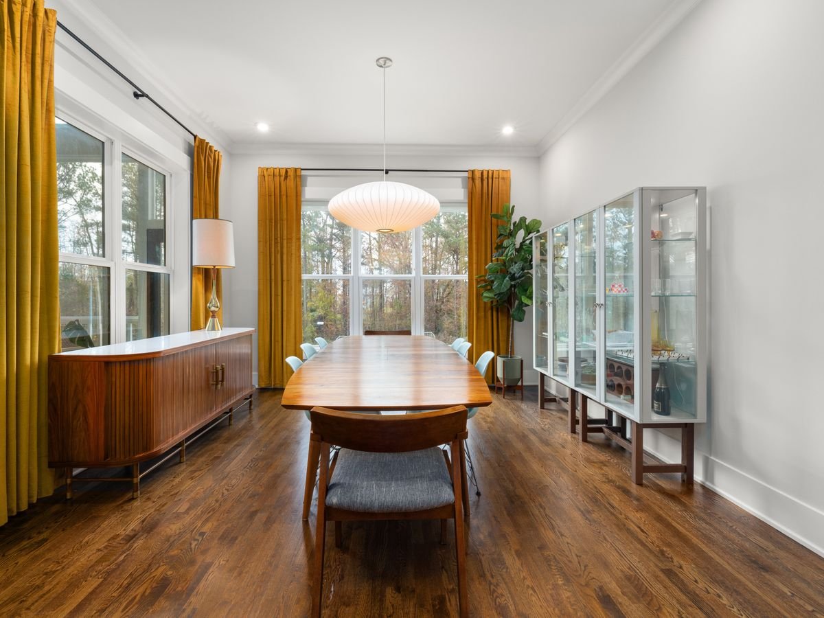 A mid-century dining room with a walnut credenza, bubble pendant and glass display cabinets